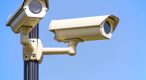 Duas câmeras de segurança montadas em poste, contra céu azul