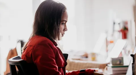 Mulher de casaco vermelho trabalhando em notebook