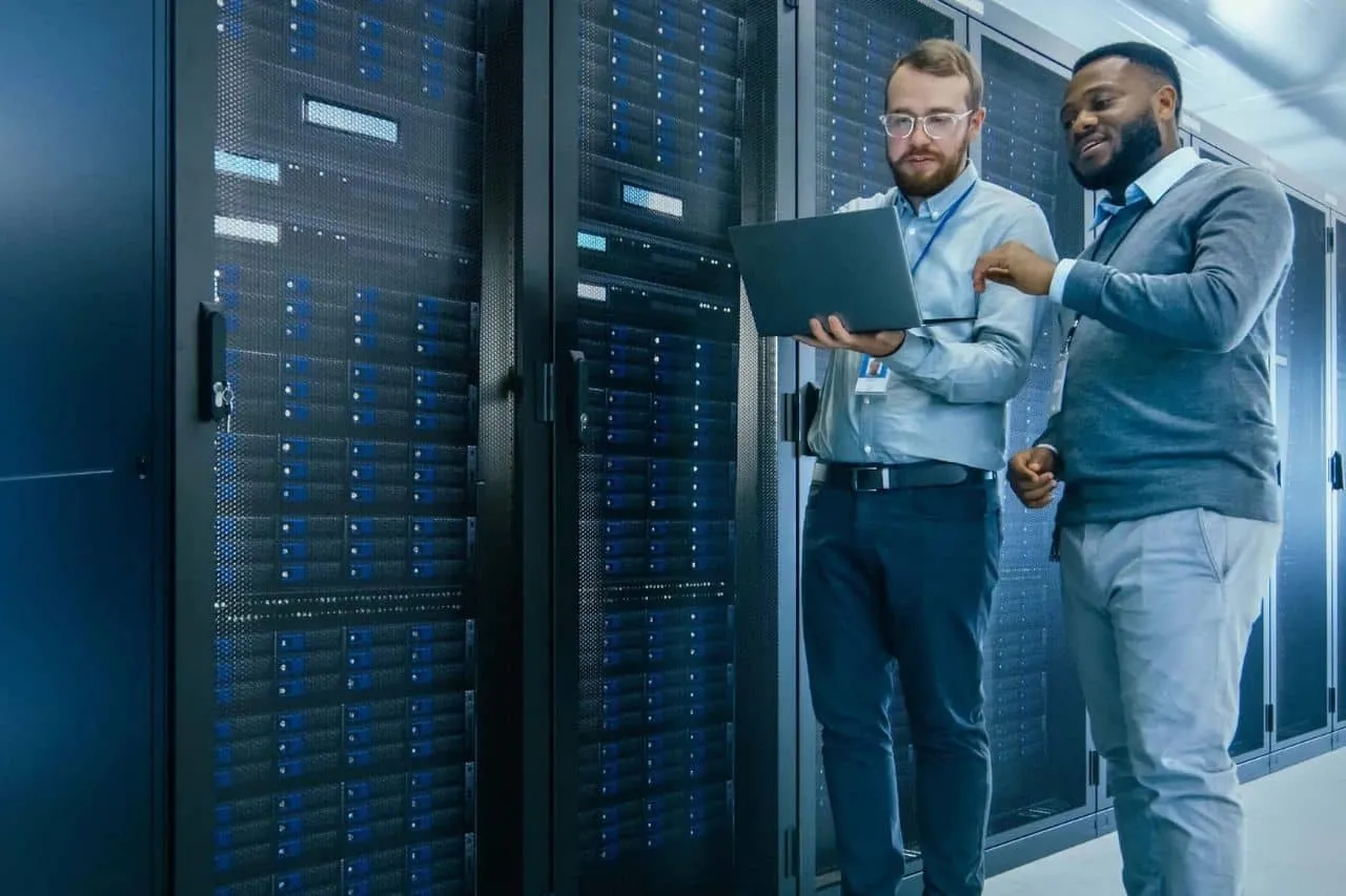 Equipe técnica da Aliança Net no corredor do data center, entre racks de servidores