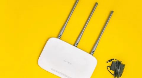 Roteador Wi-Fi de três antenas sobre fundo amarelo